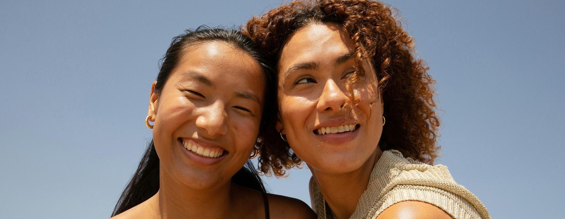 Two women smiling with a blue sky behind them.