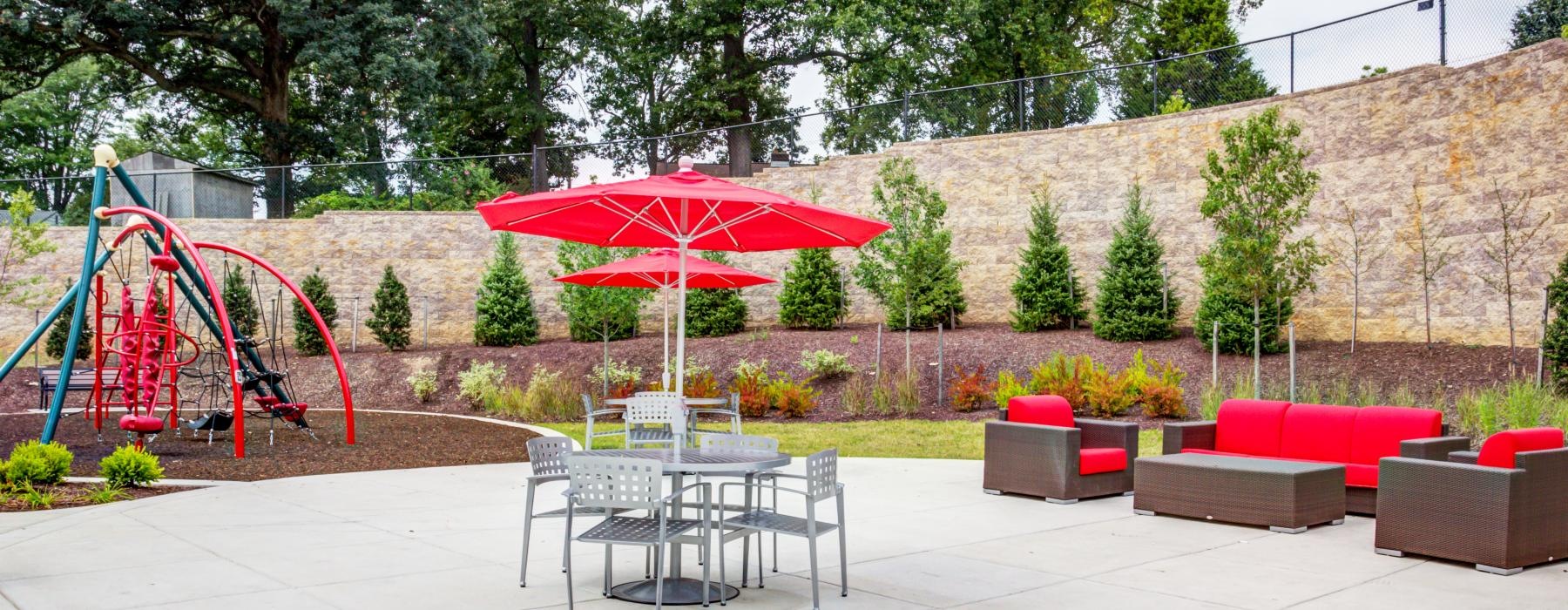 a patio with a table and chairs and a red umbrella